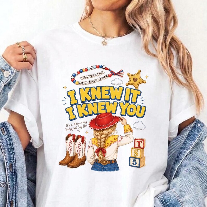 May include: A white t-shirt featuring a graphic print with the text I KNEW IT I KNEW YOU, a beaded necklace, a yellow star, a cowgirl figure in a red hat, brown cowboy boots, and three stacked blocks labeled T, S, and 5 with a small cloud icon.