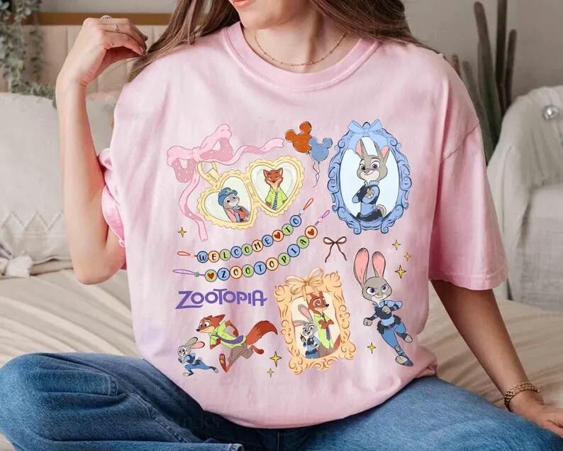 Puede incluir: Camiseta rosa claro con personajes de Zootopia y la palabra "Zootopia". El dise&ntilde;o incluye retratos enmarcados de Judy Hopps y Nick Wilde, junto con otros personajes y elementos decorativos. La camiseta es de color rosa claro.