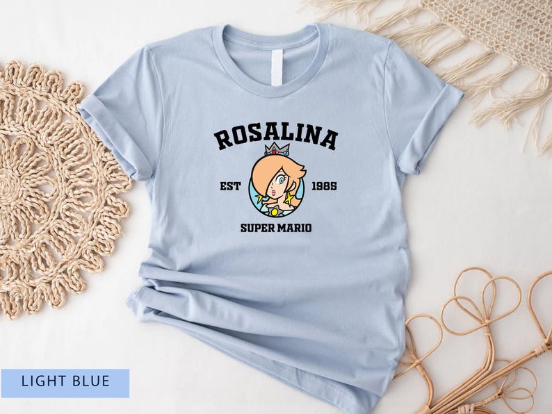 May include: Light blue t-shirt with a black graphic of Rosalina from Super Mario. The graphic includes the text "Rosalina Est 1985 Super Mario".