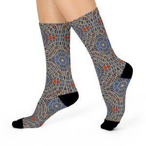 May include: A pair of patterned socks featuring a mosaic-like design in blue, yellow, and red. The socks have black heels and toes. The design includes circular and geometric shapes, creating a visually interesting pattern.