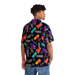 May include: A black short-sleeved button-down shirt with a geometric pattern in neon colors. The pattern includes triangles, squares, circles, and wavy lines.