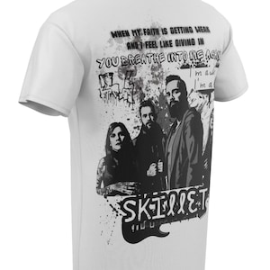 Peut inclure: T-shirt blanc avec un imprimé graphique noir et blanc d'un groupe. Le graphique comprend le nom du groupe "SKILLET" et des paroles de leur chanson "Whispers in the Dark".
