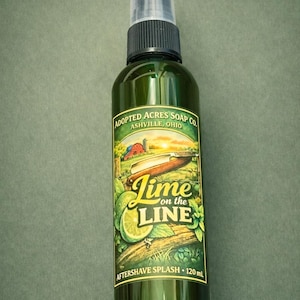 Peut inclure: Une bouteille en verre vert de lotion après-rasage avec un pulvérisateur noir. L'étiquette présente une scène de ferme avec le texte "Lime on the Line" et "Adopted Acres Soap Co."