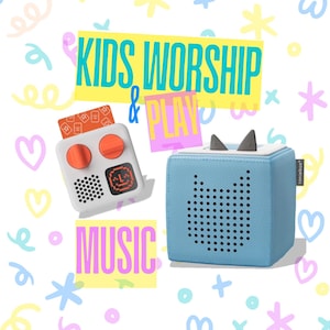 May include: A blue and white children's music player with a cat design. The player is called "Toniebox" and is next to a white and orange music player with a screen and buttons. The text "KIDS WORSHIP & PLAY MUSIC" is in the background.