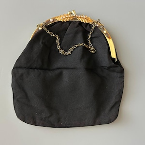 May include: Black satin evening bag with a gold-tone frame. The frame is embellished with rhinestones and a decorative leaf design. A delicate gold chain strap is attached. The bag is a classic accessory for formal events.