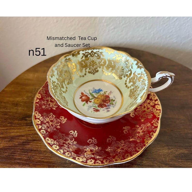 May include: A mismatched tea cup and saucer set. The cup is light green with gold filigree and a floral center. The saucer is red with gold filigree. The text "Mismatched Tea Cup and Saucer Set" and "n51" are visible.