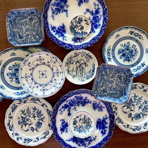 May include: A collection of blue and white porcelain plates and dishes with various floral and patterned designs. The assortment includes round plates, square dishes, and a small saucer, all with intricate detailing and a classic aesthetic.