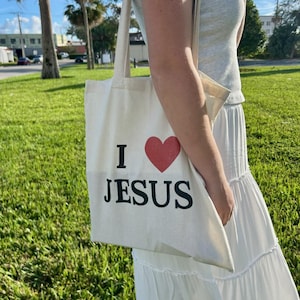 May include: A white tote bag with a red heart and the text "I love Jesus" printed on it.