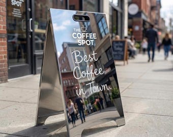Letrero publicitario tipo caballete con espejo personalizado para acera, exhibición comercial en pavimento, acabado plateado.