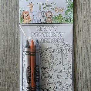 May include: A clear plastic bag contains a coloring book and three crayons. The coloring book has a jungle theme with the text "HAPPY BIRTHDAY CAMERON!" and "CAMERON IS TWO Wild". The crayons are gray, orange, and blue.