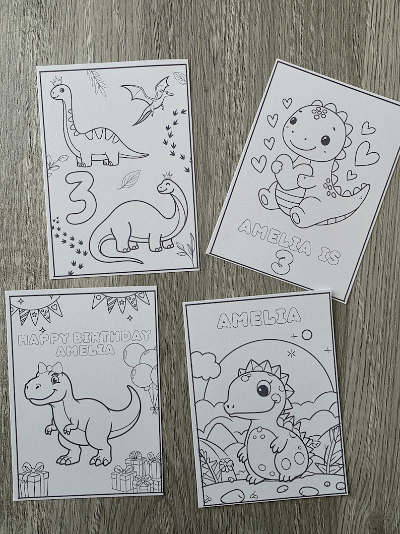 May include: Four black and white dinosaur-themed coloring pages. One page has the number 3 and two dinosaurs. Another says "AMELIA IS 3" with a dinosaur and hearts. A third says "HAPPY BIRTHDAY AMELIA" with a dinosaur and balloons. The last page says "AMELIA" with a dinosaur.