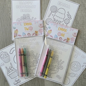 May include: A collection of birthday-themed coloring pages and crayon sets. The pages feature the name "EMMA" and the phrases "HAPPY BIRTHDAY" and "EMMA is a sweet ONE" or "TWO". The coloring pages have illustrations of sweets.