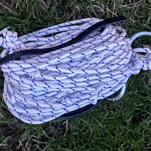 May include: A white rope with blue stripes is coiled and secured with a black strap and two silver metal rings.