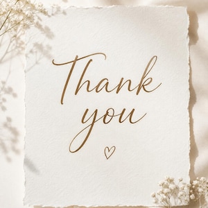 Op de afbeelding: Een vierkant vel gebroken wit, gestructureerd papier met gescheurde randen, voorzien van de bruine cursieve tekst Thank you en een klein handgetekend hartje, geaccentueerd met delicate witte gipskruidbloemen.