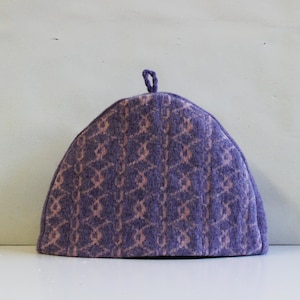 May include: Purple knitted tea cosy with a pink floral pattern.