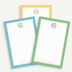 May include: Three personalized notepads in yellow, blue, and green. Each notepad has a scalloped border and a monogram in the upper center. The text "Kennedy Grayson" is printed at the bottom of each notepad.