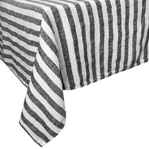 May include: A white and charcoal gray striped tablecloth. The fabric is draped over a surface, with the corner of the cloth hanging down. The stripes are vertical and evenly spaced, creating a simple, classic design.