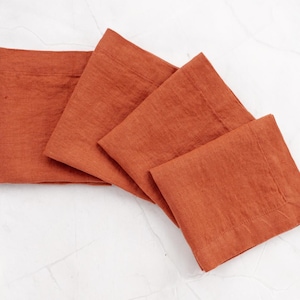 May include: Four rust-colored linen napkins folded in a square shape.