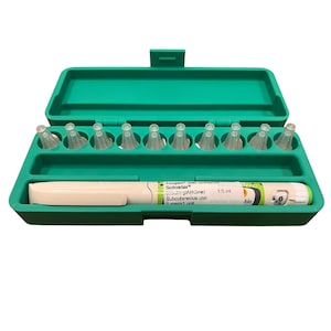 May include: A green plastic case containing a white and green Solostar insulin pen and several clear pen needles. The pen is labeled with text including "Toujeo 300 units/ml" and "Subcutaneous use".