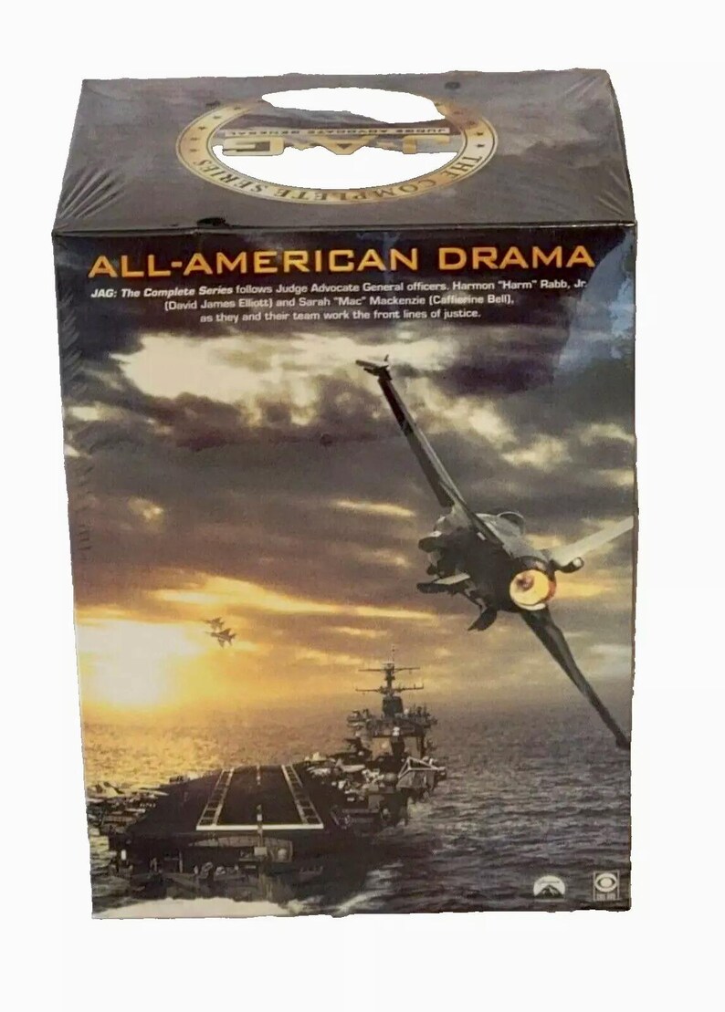 Puede incluir: Un conjunto de DVD para la serie de televisi&oacute;n JAG: All-American Drama. La caja presenta una escena de puesta de sol con un avi&oacute;n de combate volando sobre un portaaviones. El texto en la caja dice "JAG: The Complete Series follows Judge Advocate General officers. Harmon "Harm" Rabb, Jr (David James Elliott) and Sarah "Mac" Mackenzie (Catherine Bell), as they and their team work the front lines of justice."