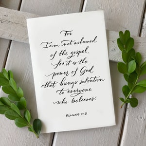 Pode incluir: Um cartão branco com elegante caligrafia preta. O texto diz: "Porque não me envergonho do evangelho, pois é o poder de Deus para a salvação de todo aquele que crê. Romanos 1:16." Folhas verdes emolduram o cartão.