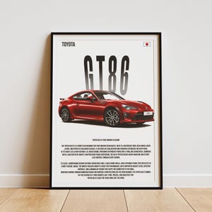 以下が含まれることがあります： 黒いホイールを装着した赤いトヨタGT86スポーツカーと、黒い背景に白い文字で「TOYOTA GT86」と書かれたポスター。ポスターの右上には日本の国旗が描かれている。
