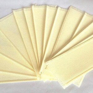 May include: A set of ten off-white fabric squares, arranged in a fan shape. The squares are made of a woven material with a slightly textured surface.