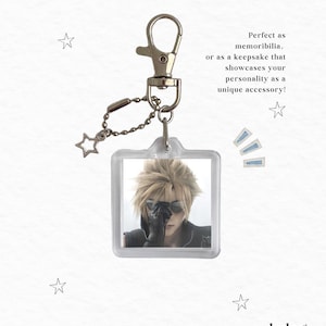 May include: A square acrylic keychain featuring a character with spiky blonde hair and dark sunglasses. The keychain includes a silver-toned metal lobster clasp and a small chain with a star-shaped charm. Text on the image reads: Perfect as memorabilia, or as a keepsake that showcases your personality as a unique accessory! and lucky dream studios.