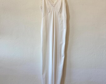 Puede incluir: Un vestido blanco de slip con ribete de encaje en el escote y el dobladillo.