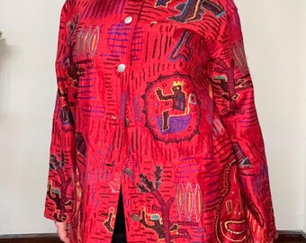 Puede incluir: Una camisa roja de botones con un diseño bordado de colores que presenta formas geométricas, figuras y plantas. La camisa tiene manga larga y un corte holgado.