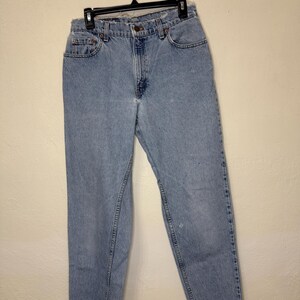 May include: Light blue denim jeans with a straight leg fit. The jeans have a frayed hem and a classic five-pocket design.