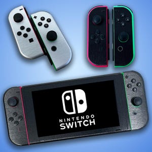 Puede incluir: Una consola Nintendo Switch negra con un logotipo Nintendo Switch blanco y el texto "NINTENDO SWITCH". La consola tiene una pantalla negra y dos mandos grises con botones negros. Los mandos tienen detalles verdes y rosas.