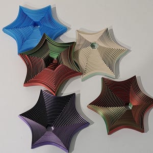 May include: Five paper stars in different colors, including blue, green, beige, red, and purple. Each star is made of multiple layers of paper, creating a 3D effect.