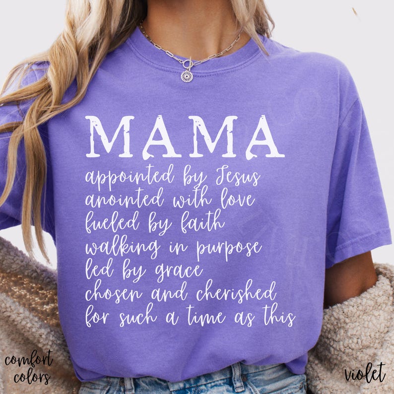 May include: A violet-colored t-shirt with the word "MAMA" in large white letters. Below, smaller white text reads "appointed by Jesus, anointed with love, fueled by faith, walking in purpose, led by grace, chosen and cherished for such a time as this."