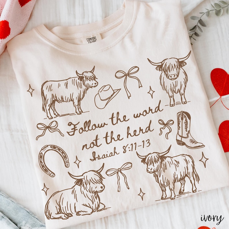 May include: Ivory-colored sweatshirt with a brown graphic design featuring Highland cows, a cowboy hat, a horseshoe, a cowboy boot, and bows. The text "Follow the word not the herd Isaiah 8:11-13" is also printed on the shirt.