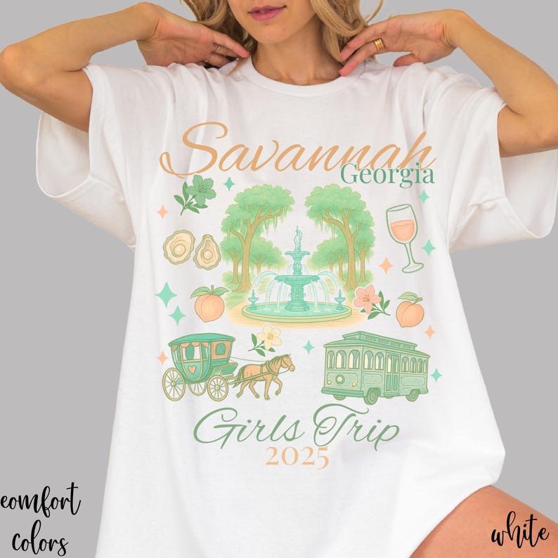 May include: White t-shirt with a colorful graphic design featuring the text "Savannah Georgia Girls Trip 2025." The design includes illustrations of a fountain, peach, wine glass, and a horse-drawn carriage.
