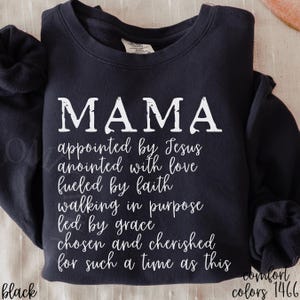 May include: Black sweatshirt with the word "MAMA" in large white letters. Below, the text reads "appointed by Jesus, anointed with love, fueled by faith, walking in purpose, led by grace, chosen and cherished for such a time as this."