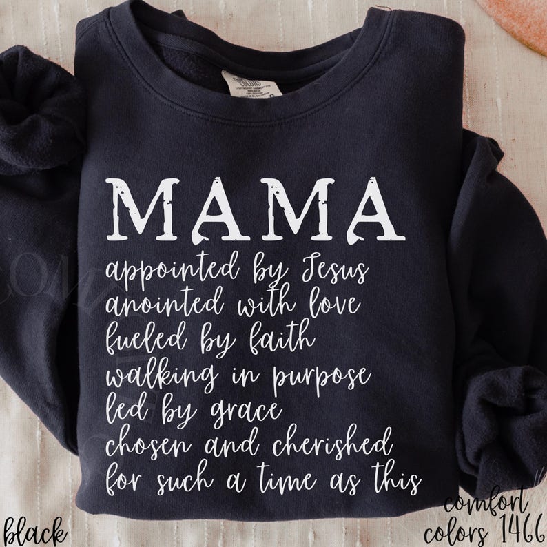 May include: Black sweatshirt with the word "MAMA" in large white letters. Below, the text reads "appointed by Jesus, anointed with love, fueled by faith, walking in purpose, led by grace, chosen and cherished for such a time as this."