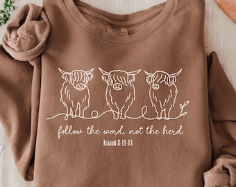 May include: Espresso-colored sweatshirt with a white graphic of three Highland cows and the text "follow the word, not the herd" and "ISAIAH 8:11-13". The sweatshirt is a Comfort Colors 1466 style.