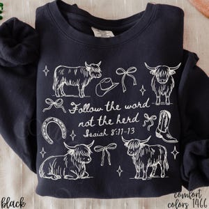 May include: Black sweatshirt with a white graphic design featuring Highland cows, a cowboy hat, bows, a horseshoe, and a cowboy boot. The text "Follow the word not the herd Isaiah 8:11-13" is also included.