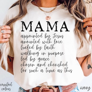 May include: Ivory-colored t-shirt with the word "MAMA" in large, black letters. Below, a list of inspirational phrases is printed in a script font. The words "comfort colors" and "ivory" are also visible.
