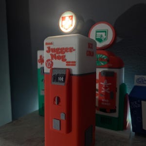 May include: A red and white Juggernog vending machine with a glowing top, featuring the text "Drink Juggernog 10p". Other vending machines are visible in the background, including one with the text "Ice Cold".