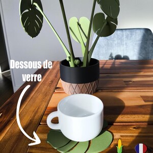 Peut inclure: Une plante monstera verte en maïs, avec un pot noir et brun, et une tasse blanche sur un dessous de verre en feuille de monstera verte. Le texte "Dessous de verre" est visible sur l'image. Le texte "@Touche3D" est visible sur l'image. Le texte "Fait en Mais" est visible sur l'image. Le texte "Made in France" est visible sur l'image.