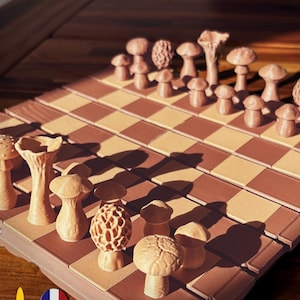 Può includere: Un esclusivo set di scacchi con pezzi a forma di fungo nei toni del beige e del marrone. La scacchiera presenta un classico motivo a scacchiera nei colori coordinati. Include il testo "Made in France" e "@Touche3D".
