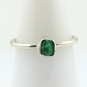 Puede incluir: Un anillo de plata con una piedra preciosa verde engastada en forma cuadrada.
