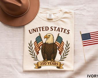 アメリカ建国250周年記念コンフォートカラーUSAシャツ、レディース愛国心あふれるイーグルTシャツ、アメリカ合衆国建国250周年記念500周年記念国旗シャツ