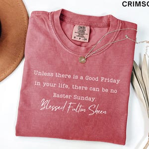 May include: Crimson t-shirt featuring the quote "Unless there is a Good Friday in your life, there can be no Easter Sunday. Blessed Fulton Sheen." A gold pendant necklace and a brown hat are also visible.