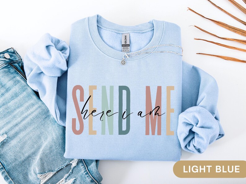 May include: Light blue sweatshirt with the text "SEND ME here i am" in colorful letters.