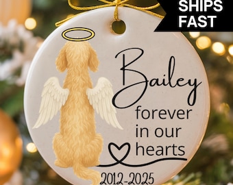 May include: A circular ceramic ornament with a golden dog design, angel wings, and a halo. The ornament reads "Bailey, forever in our hearts" with the years "2012-2025". It has a gold ribbon for hanging. The ornament is white.