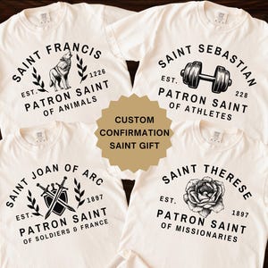 May include: Four white t-shirts with black text and images. Each shirt features a different saint and their patron saint title. The saints are Saint Francis, Saint Sebastian, Saint Joan of Arc, and Saint Therese. The shirts are a custom confirmation gift.